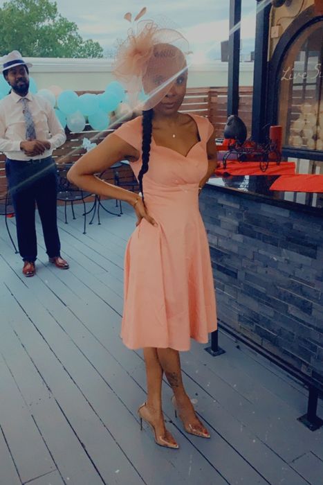 A reviewer models the dress in a soft peach color.