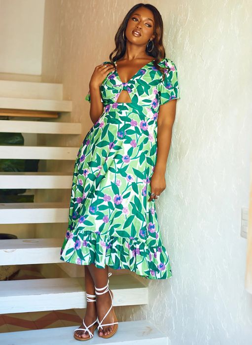 A model is seen wearing a gorgeous orchid floral print dress paired with white sandals.