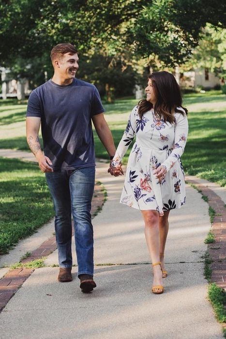 A reviewer steps out in the white floral dress, walking with grace.