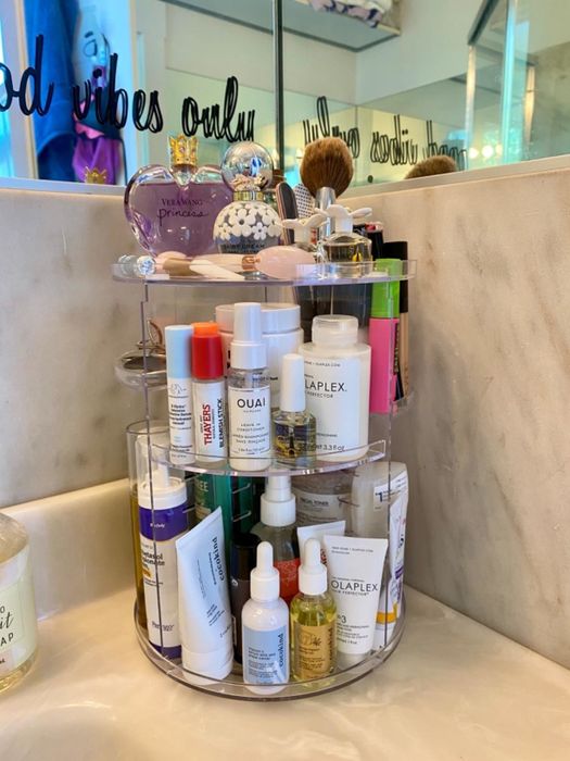 reviewer's clear rotating plastic makeup organizer displaying skincare products and perfume