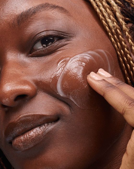a model gently massages Glossier Milky Jelly Cleanser onto their skin