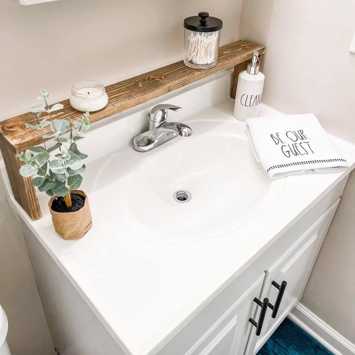 wooden rack placed above the kitchen sink, holding a candle and a jar
