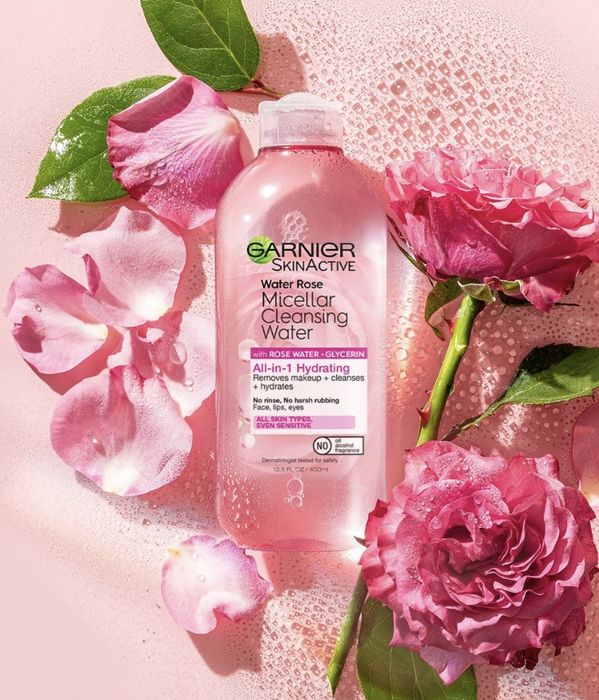 the micellar water placed next to pink roses and scattered rose petals
