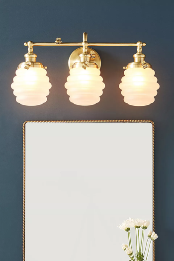 A set of three beehive-inspired sconces mounted above a mirror
