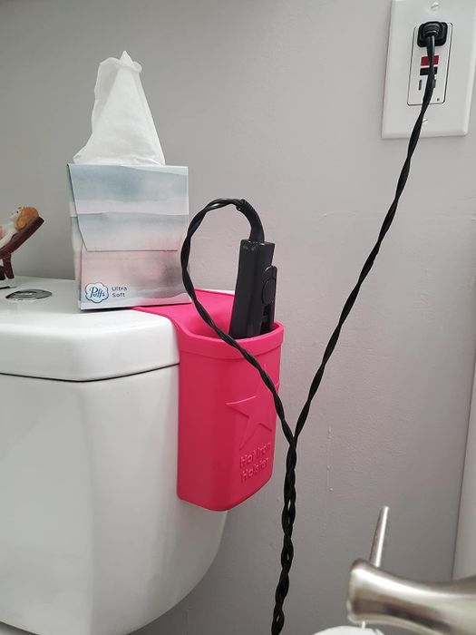 reviewer demonstrating a pink hot iron holder with a flat iron plugged in