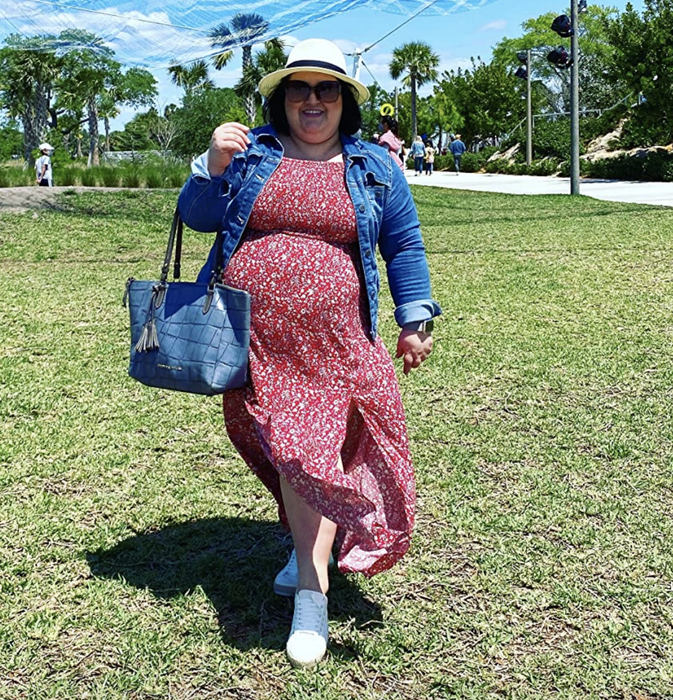 A reviewer is wearing a red dress paired with a denim jacket.