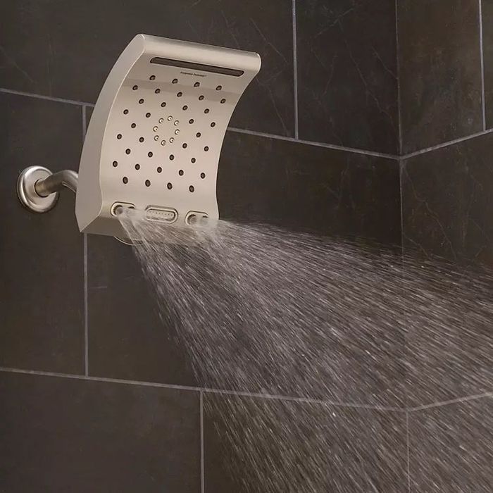 A gold rain showerhead releasing a gentle spray of water in a shower.