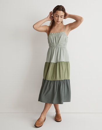 A model wearing a tiered colorblock midi dress in three shades of green.