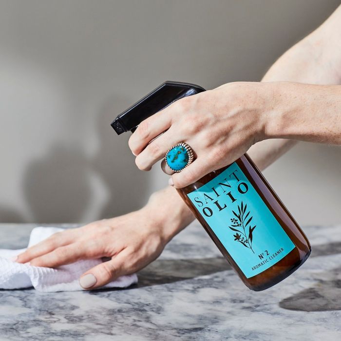 A hand using the aromatic cleaner to wipe down a marble surface.