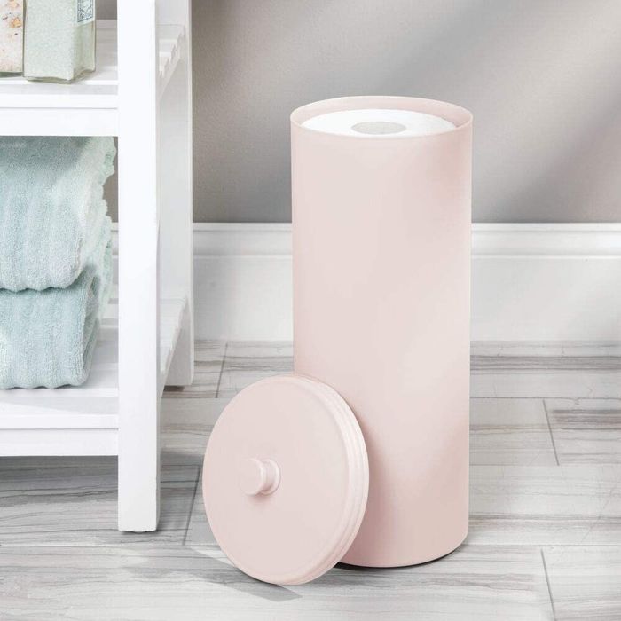The pink canister for storing extra toilet paper.