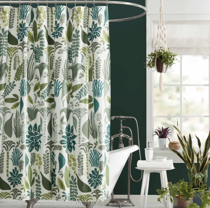 The shower curtain, adorned with a leafy pattern, is displayed in a bathroom setting.
