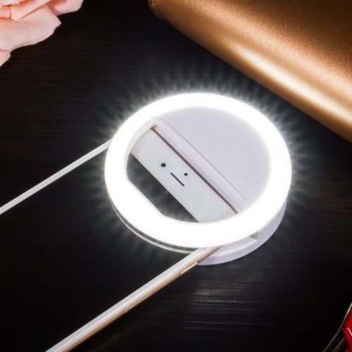 A selfie ring light illuminated and clipped onto a phone, ready to enhance your photo game.