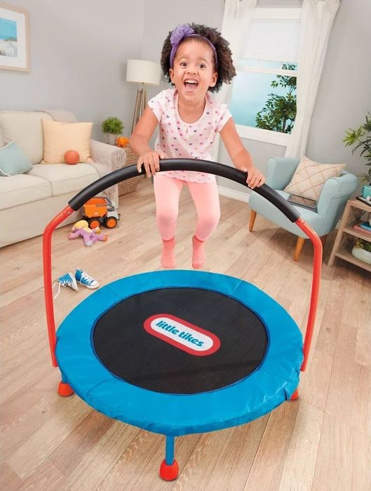 A child joyfully bouncing on a blue, black, and red mini trampoline