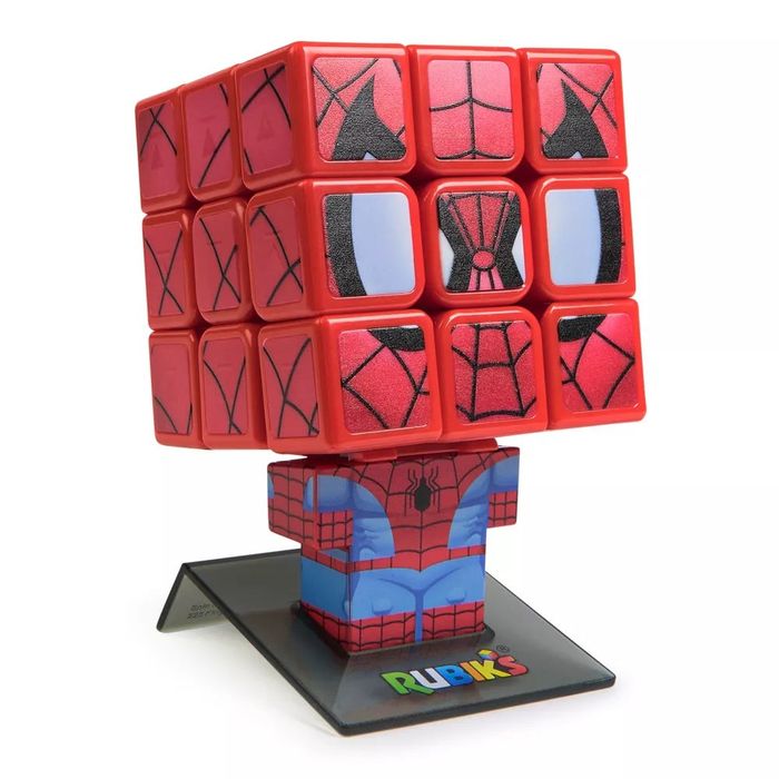 A Spider-Man themed Rubik's Cube is displayed on a stand, showing off its distinctive spider web patterns and Spider-Man's face across the individual cube sections.