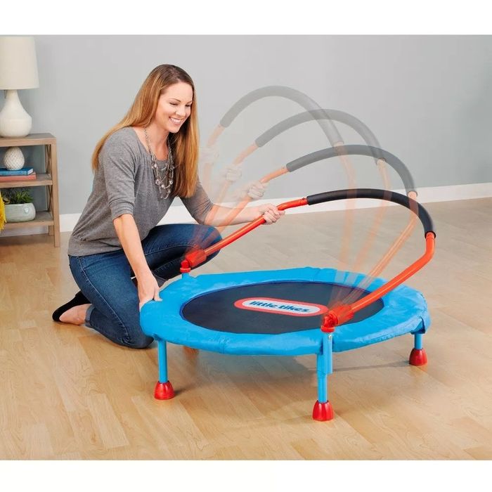 An adult model demonstrating how the trampoline easily folds down for compact storage.