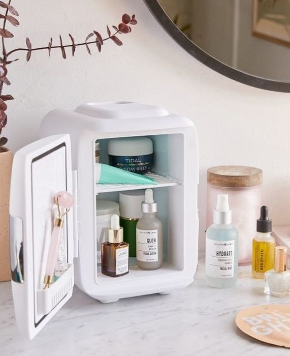 A mini fridge opened to reveal a variety of beauty products neatly organized on the shelf inside.