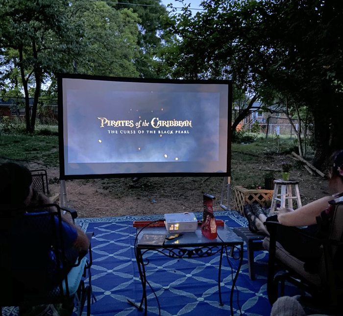 A reviewer captures a backyard setup with a screen and the projector playing a movie, creating the perfect outdoor cinema.