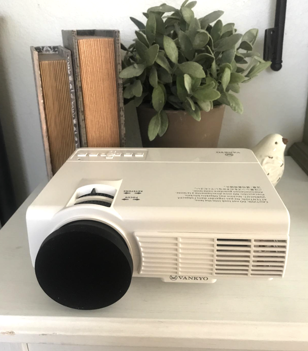 A reviewer shows off the Vankyo projector in use, ready for an outdoor movie experience.