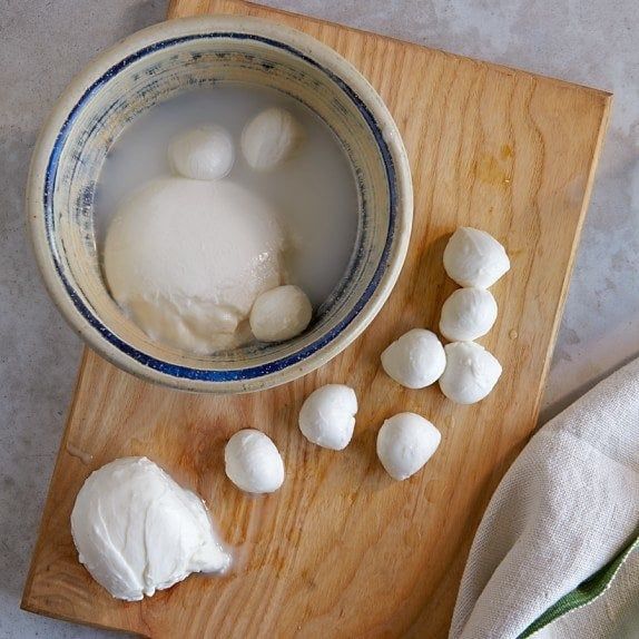 Mozzarella balls soaking and being chopped into small pieces