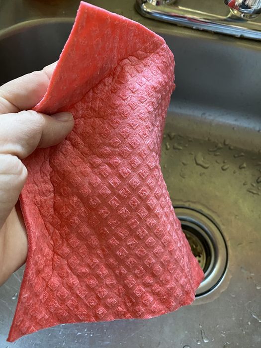 A reviewer is holding a pink dishcloth in their hands.