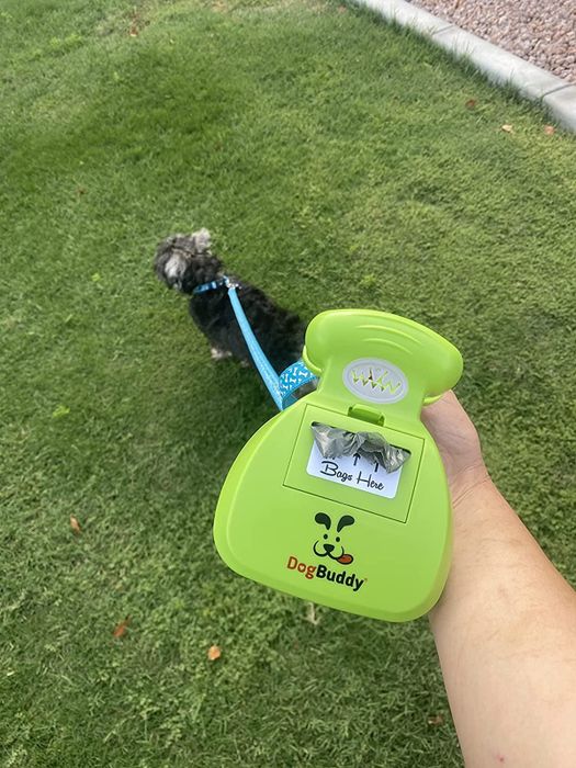 A reviewer holding the DogBuddy pooper scooper, with bags attached to their dog's leash.