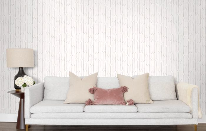 A couch positioned against a wall adorned with white and grey geometric-patterned wallpaper