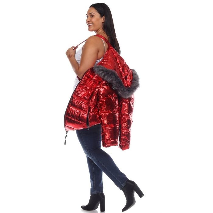 A person holding a metallic red puffer jacket by its inner carrying straps, ready to take it off.