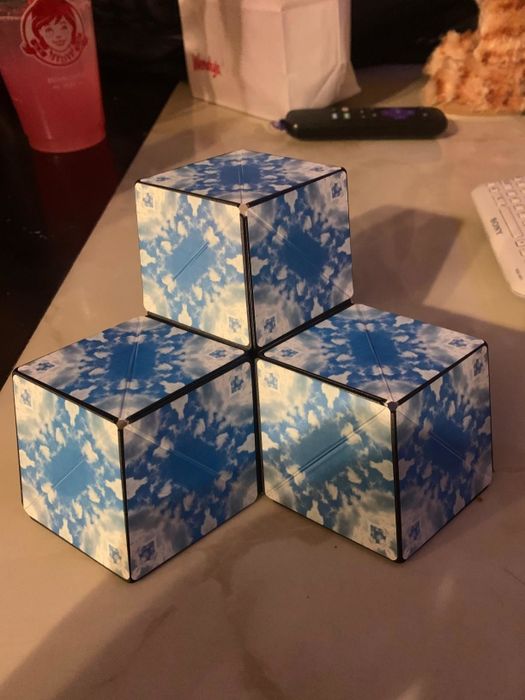 The reviewer demonstrates the fidget cube in its expanded form, now transformed into several smaller cubes.