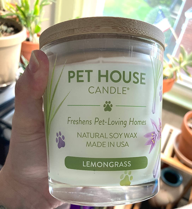 A reviewer showing off the lemongrass-scented candle.