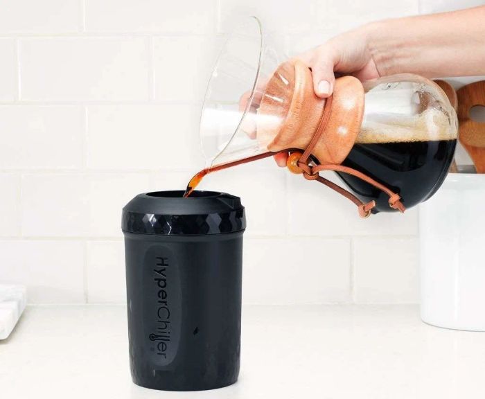 A hand transferring freshly brewed coffee from a pourover into the HyperChiller canister