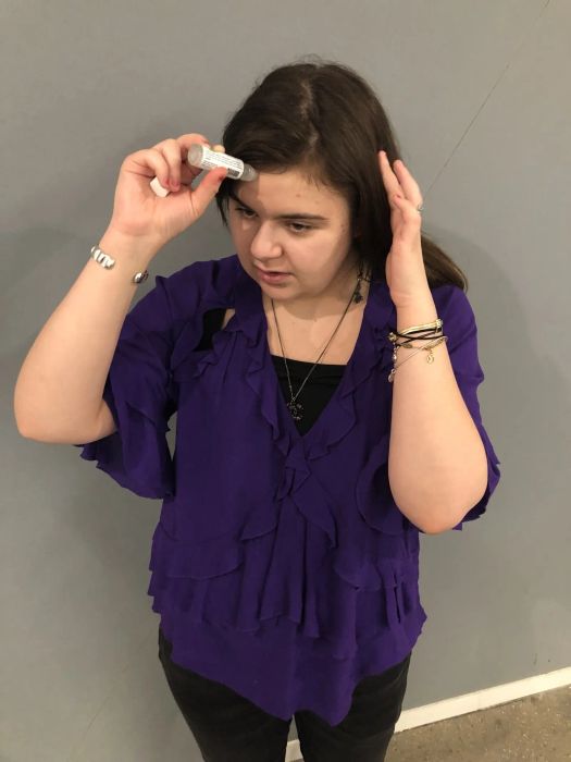 A reviewer applying the roll-on stick to her forehead.