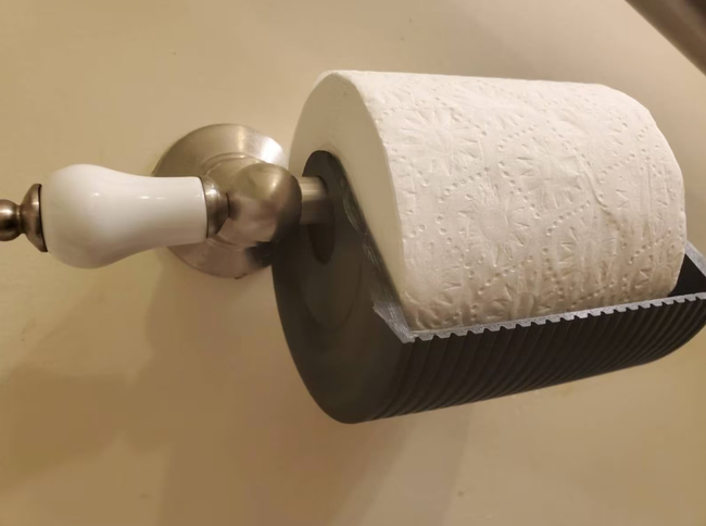 A black plastic cover around the bottom of a toilet paper roll.