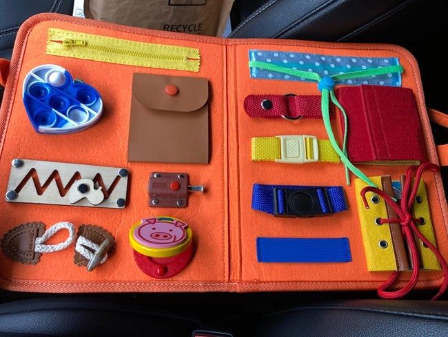 A photo showing the open busy board featuring an array of buckles, zippers, ties, and buttons.