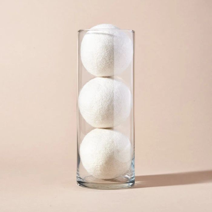 A glass vase showcasing three large white wool dryer balls