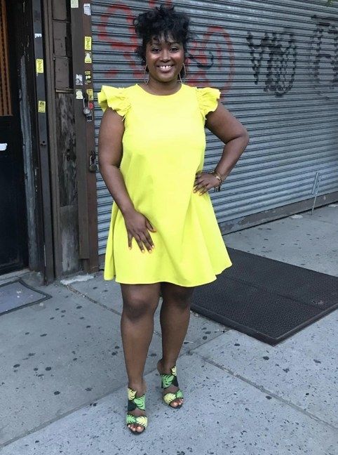 A reviewer wearing a yellow dress with ruffled sleeves, exuding a cheerful vibe.