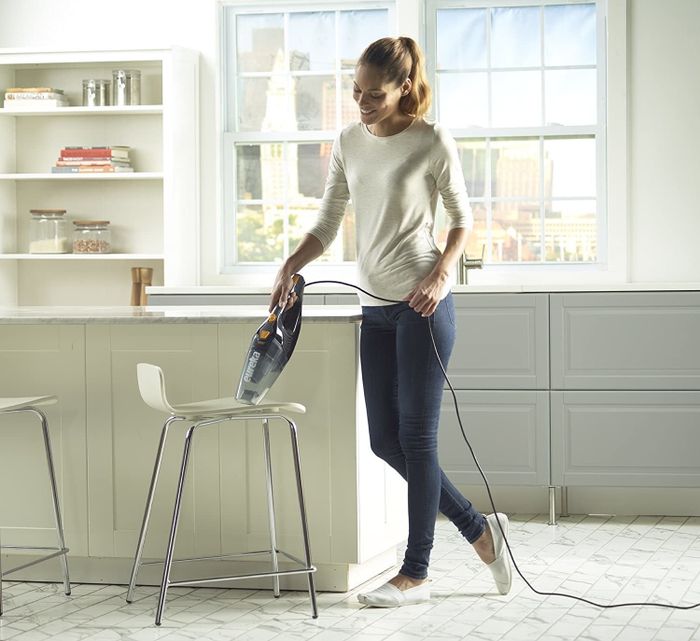 A model using the vacuum in handheld mode on a chair