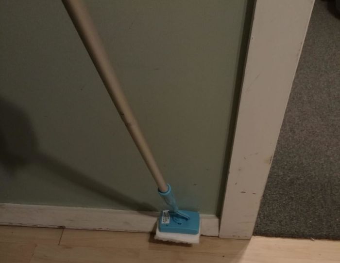An Amazon reviewer using the Baseboard Buddy extended to clean a baseboard