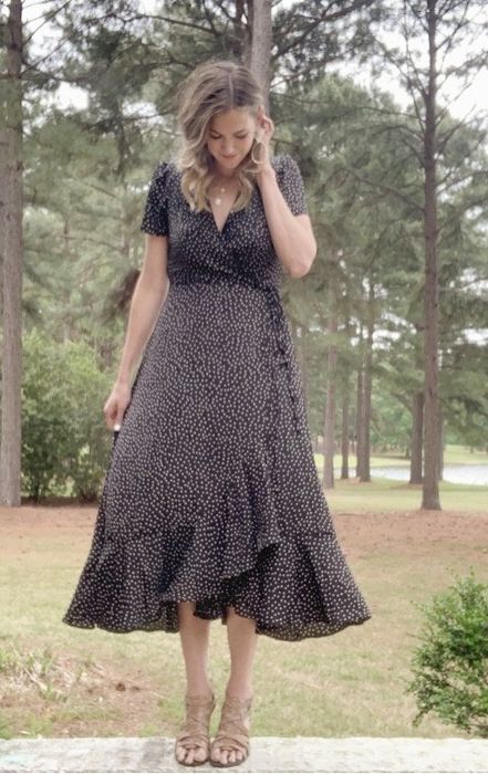 A reviewer dressed in a black long wrap dress.