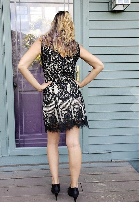 A reviewer showcases a black lace dress, focusing on the back view.
