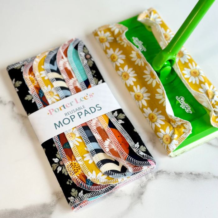 A pack of reusable mop pads placed next to a Swiffer