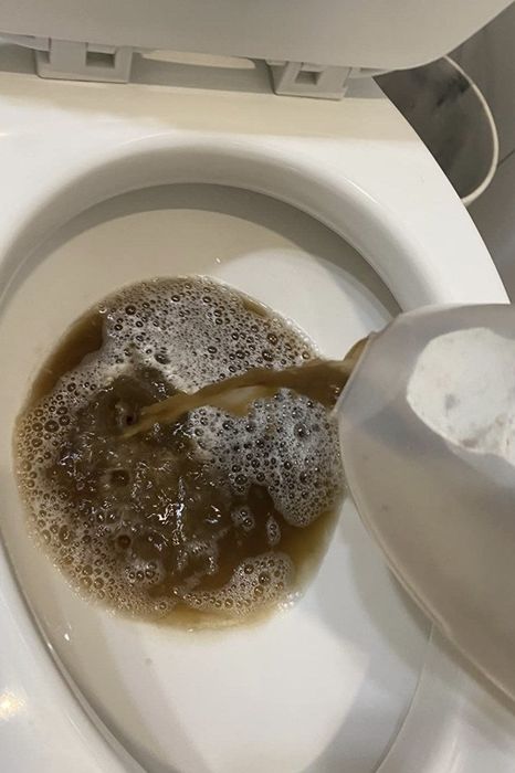 A reviewer pouring out the dirty water collected in the machine after cleaning.