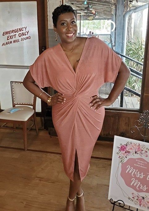A reviewer in a vibrant pink twist knot dress