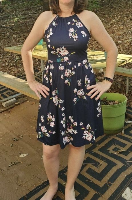 A reviewer wearing a floral knee-length dress.