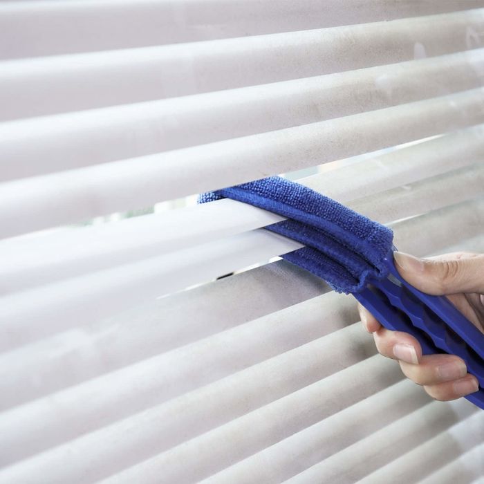 A model using a three-pronged cleaner to swipe across blinds