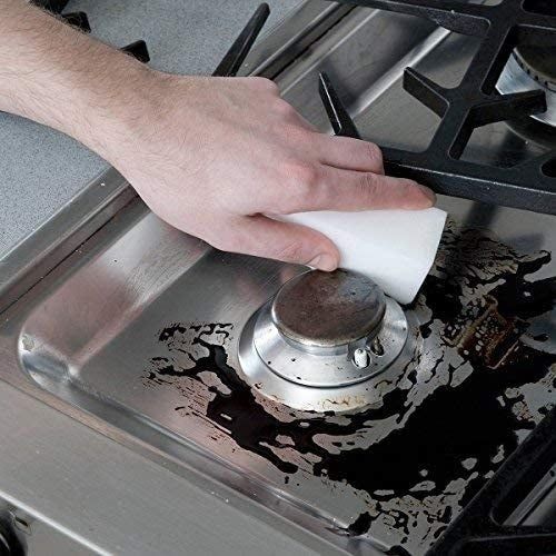 A thick white cleaning pad being applied to scrub a stove burner.