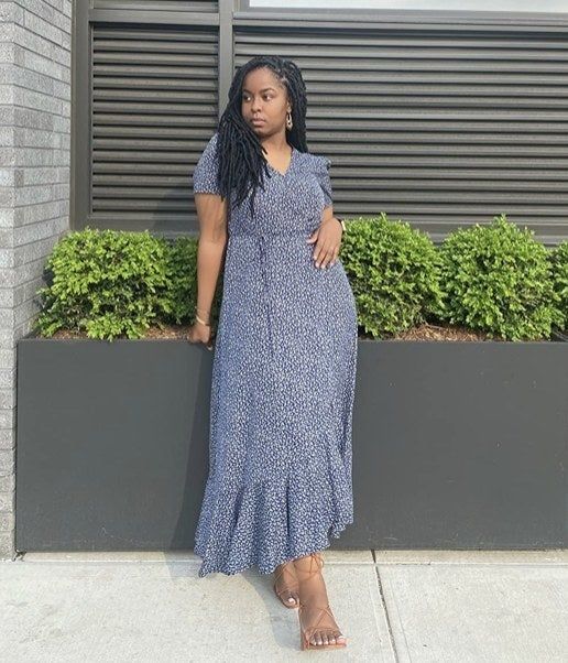 A reviewer wearing a blue long wrap dress.