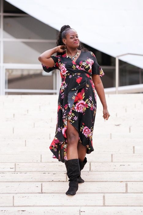 A reviewer wearing a black floral dress.