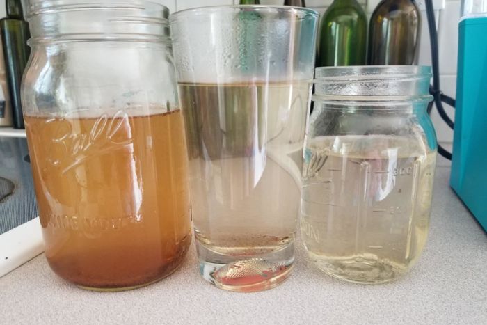 A reviewer’s photo depicting three jars filled with cleaner and water that has been run through the Keurig using a cleaning pod