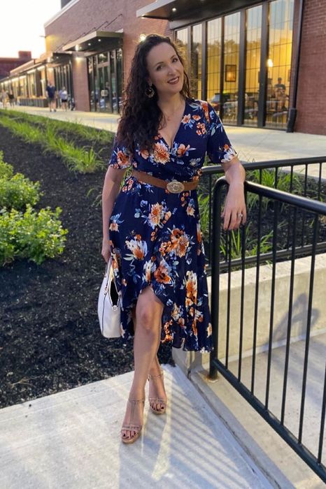 A reviewer showcasing a blue floral dress.