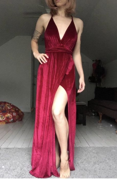 A reviewer wearing a red, floor-length dress featuring a slit.